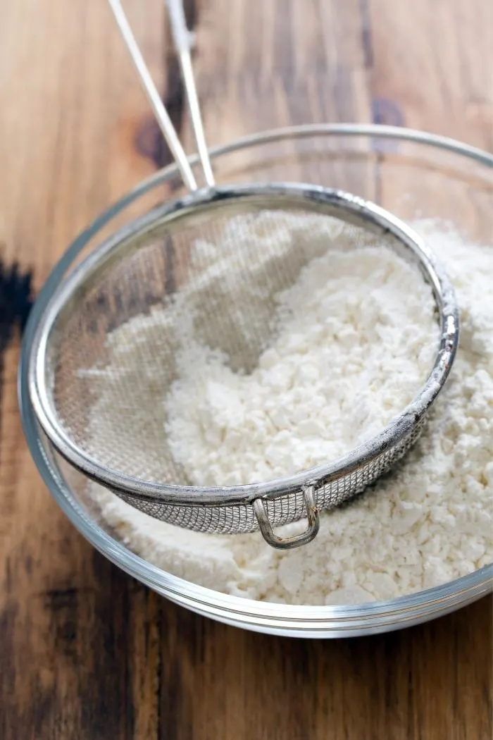 sifting flour in a glass bowl