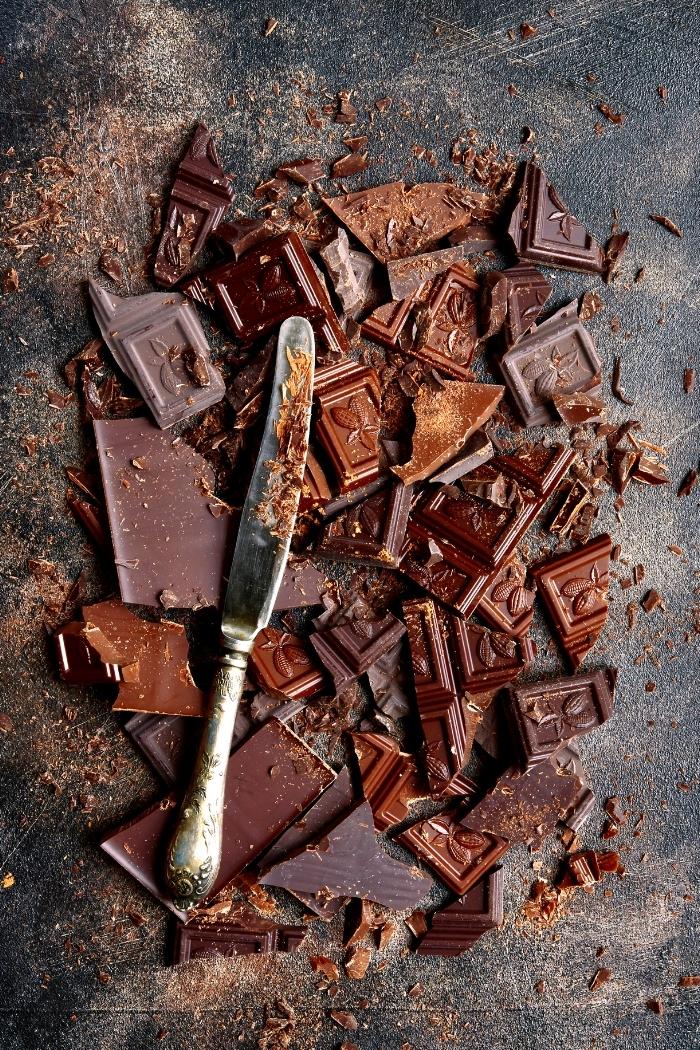 chopped dark and milk chocolate bars on a dark background with a knife