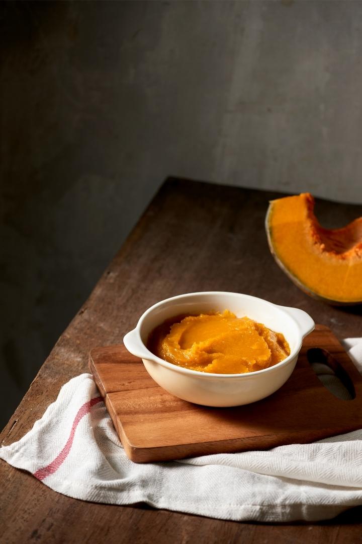 white bowl with pumpkin puree on wooden table