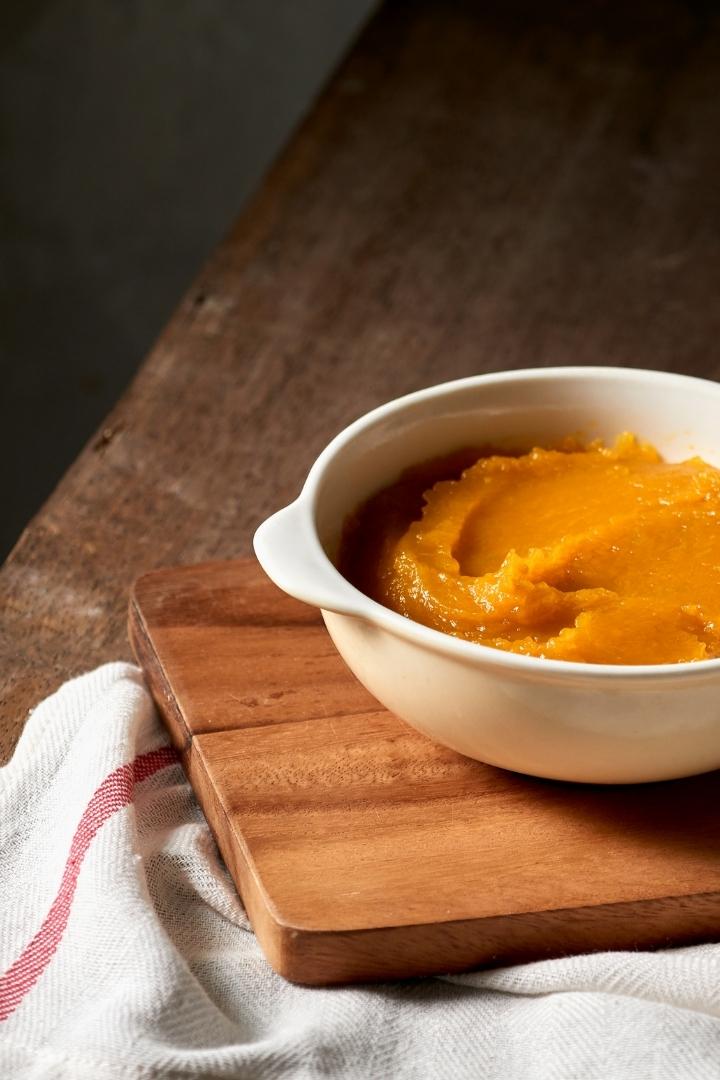 white bowl with pumpkin puree on wooden table