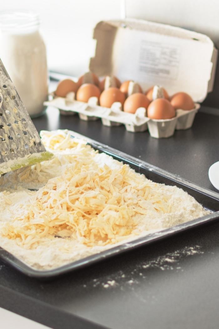 someone grating butter with a box grater on a kitchen counter