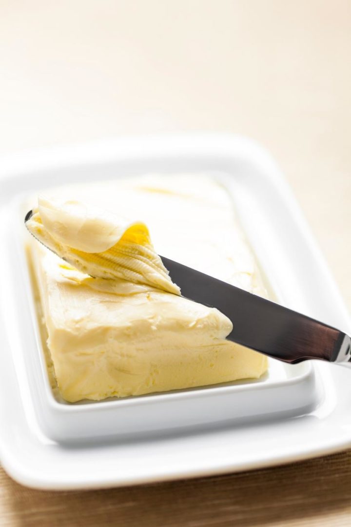 soft butter on a white butter dish with a knife