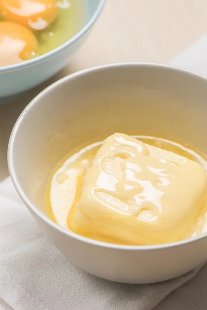 partially melted butter in a white bowl on a kitchen counter