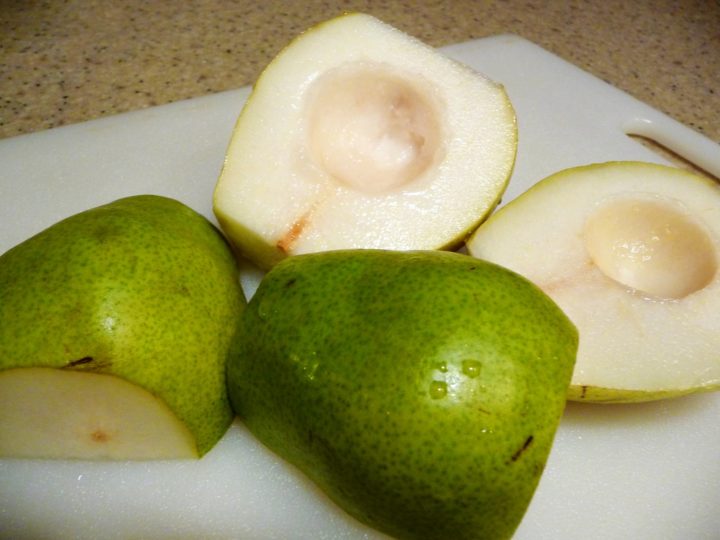 Two pears, halved on a cutting board. 