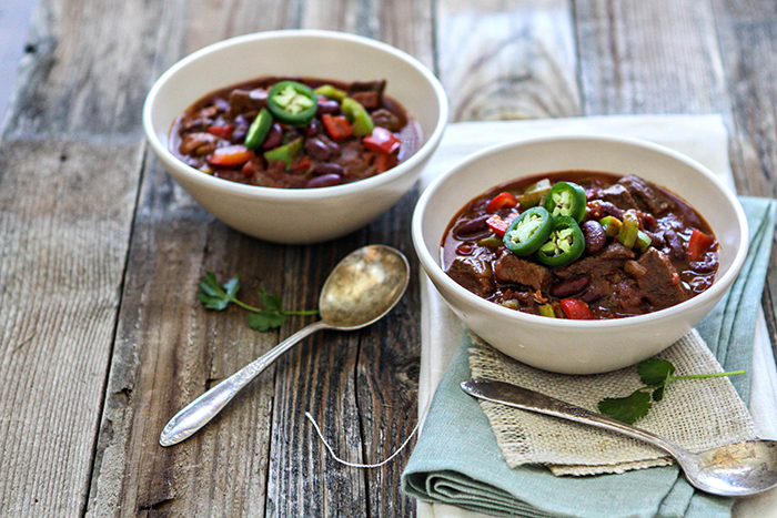 two bowls of chili with beef short rib on a rustic wooden table