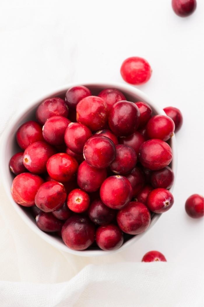 overhead shot of cranberries in a white bowl on a white background