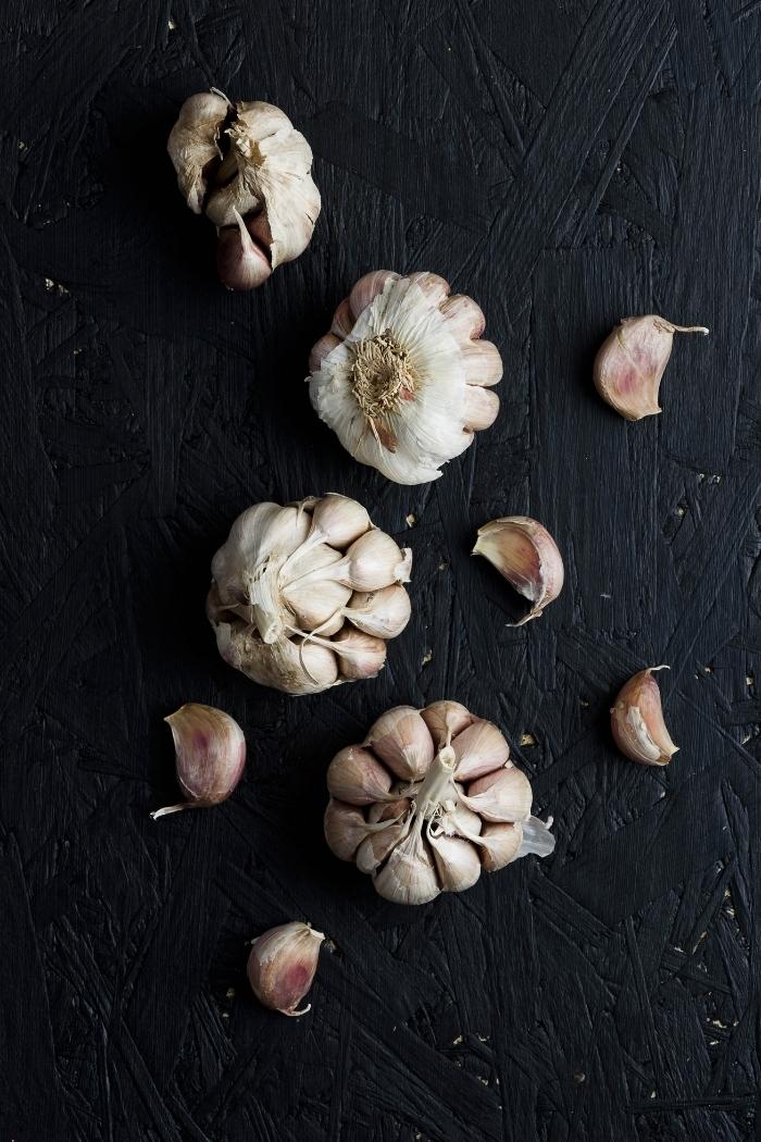 photo of garlic cloves on a dark background to use to make roasted sweet potato cubes