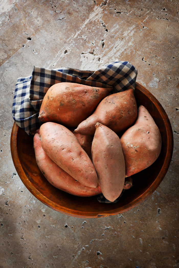 photo of uncooked sweet potatoes in a bowl with a tea towel for sweet potato recipes