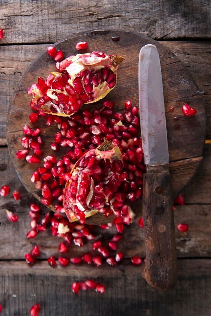 cut pomegranate with knife on cutting board to use to make this pomegranate appetizer recipe