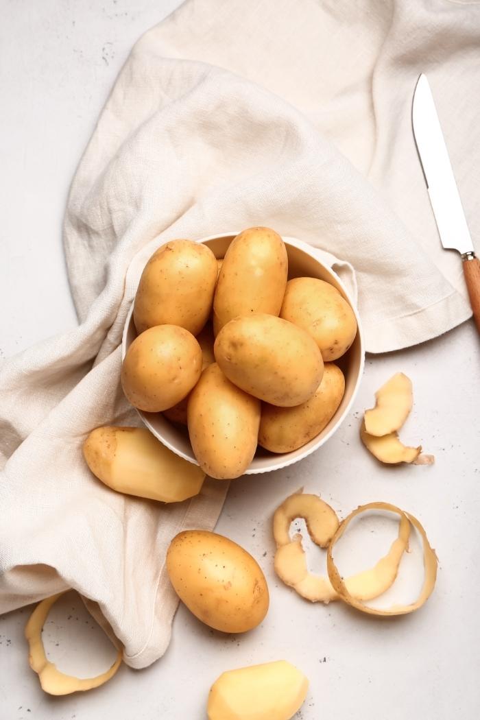 overhead shot of potatoes in a white bowl on a light background
