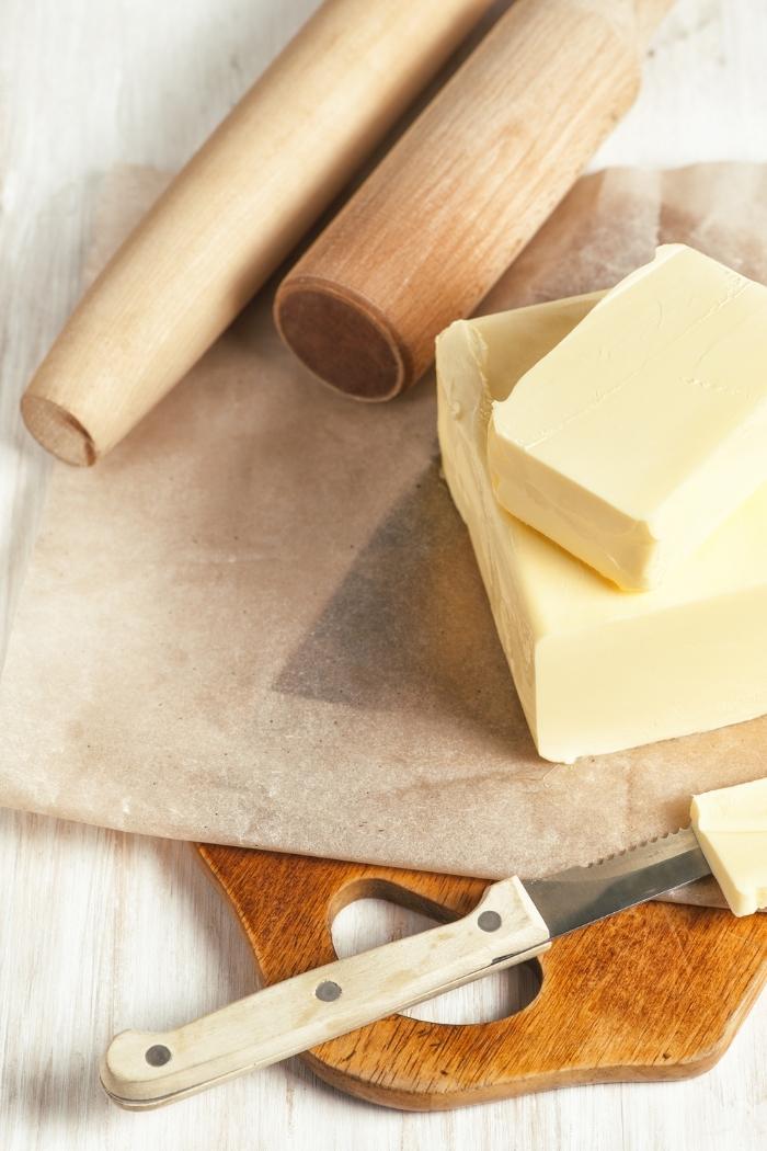 butter on a cutting board with wooden rolling pins and a knife