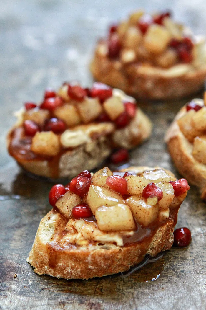 crostini with pear and pomegranate on baking sheet