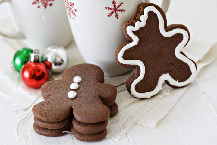 a stack of chocolate gingerbread cookies next to christmas mugs