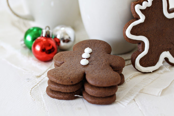 a stack of chocolate gingerbread cookies next to christmas mugs
