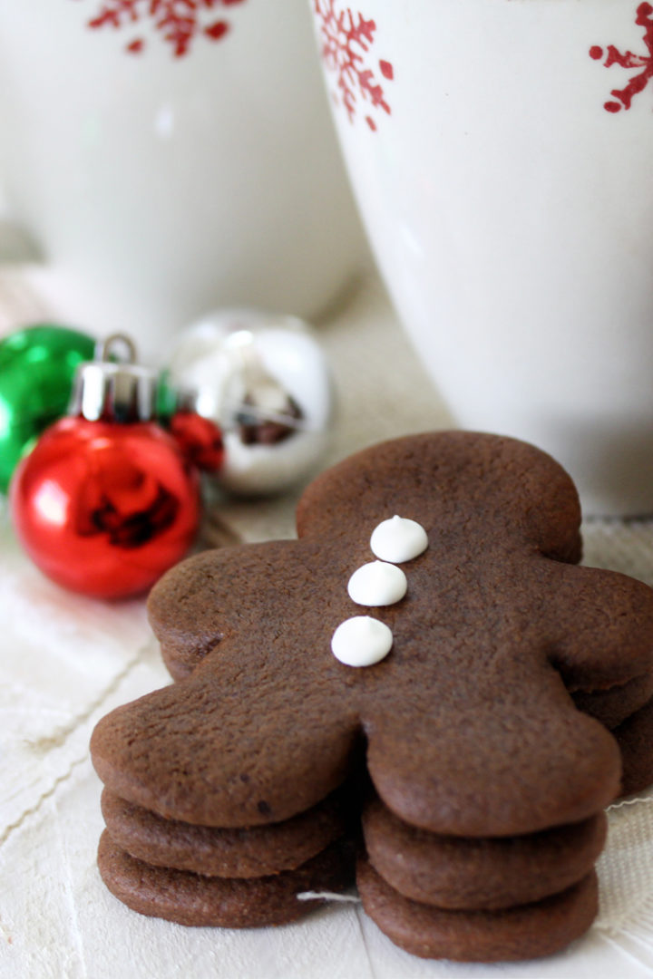 a stack of chocolate gingerbread cookies next to christmas mugs