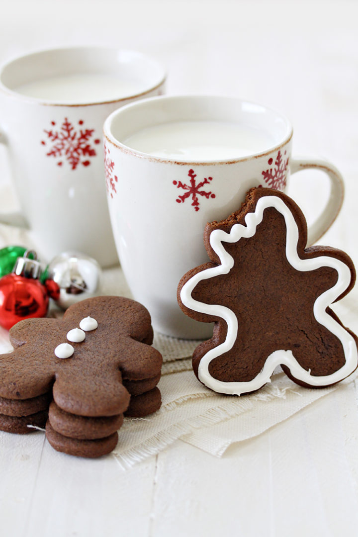 a stack of chocolate gingerbread cookies next to christmas mugs