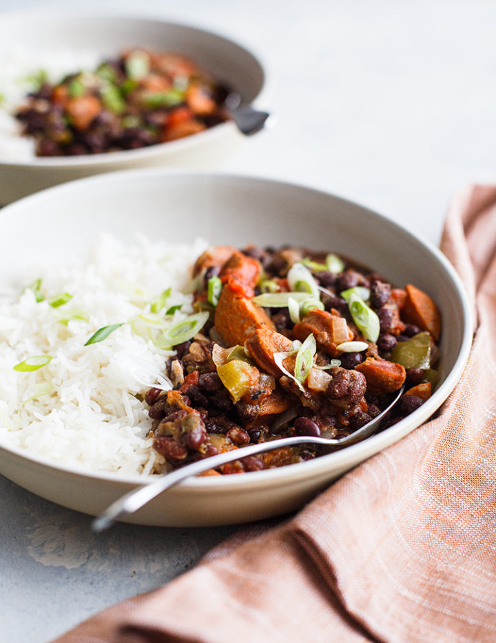 white bowls of black beans and rice on a table with linens