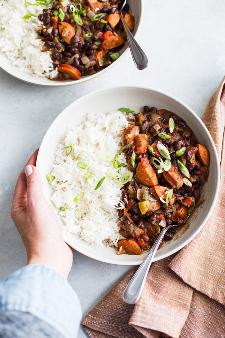 woman with hands on a bowl of black beans and rice