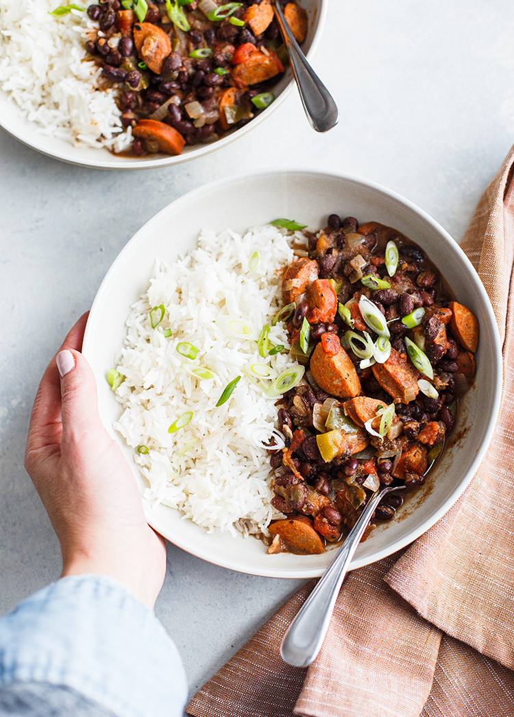 overhead shot of bowl with black beans and rice and woman's hands