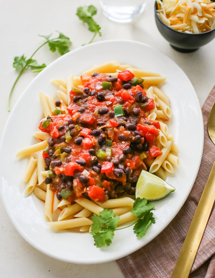 white platter with pasta and black bean sauce on a table