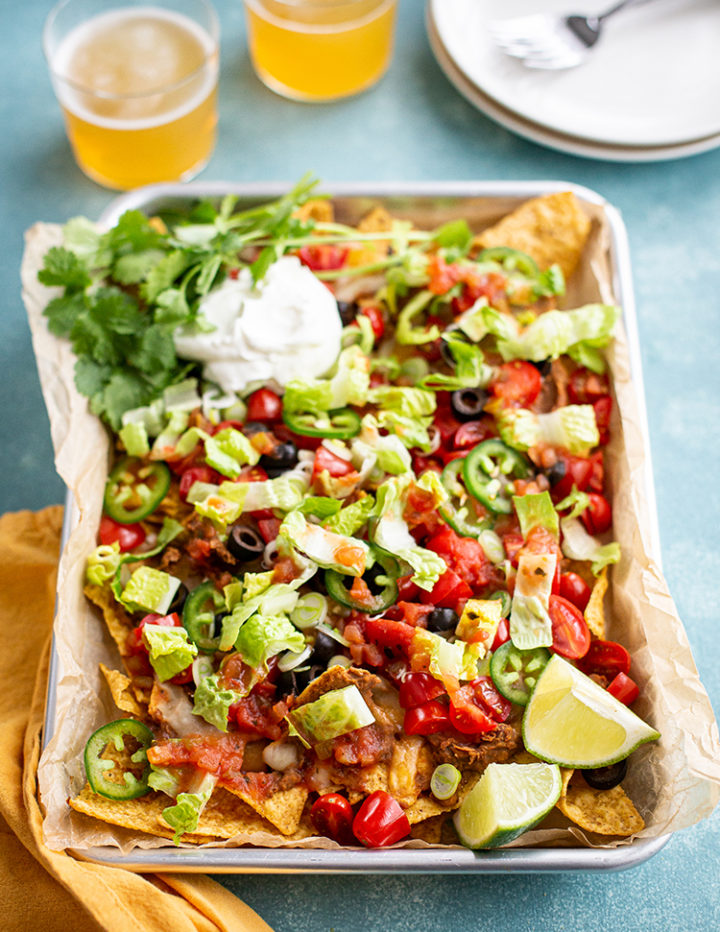 baking sheet of this baked nachos recipe on a blue background