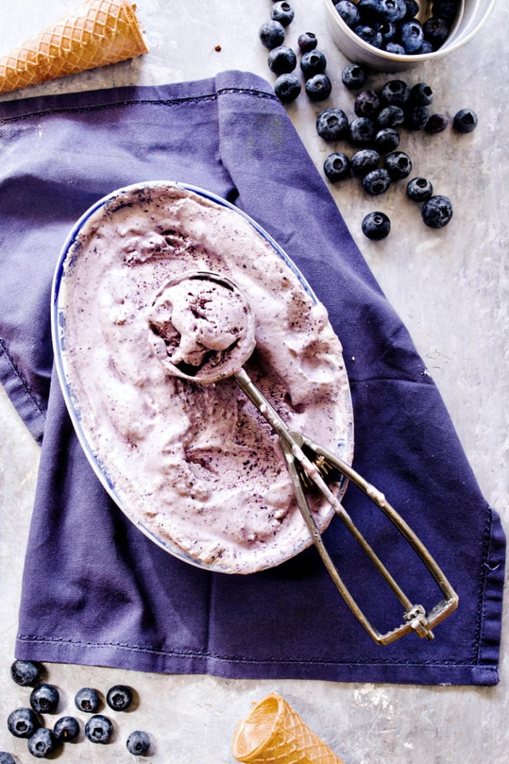 overhead shot of blueberry cheesecake ice cream in a container with an ice cream scoop