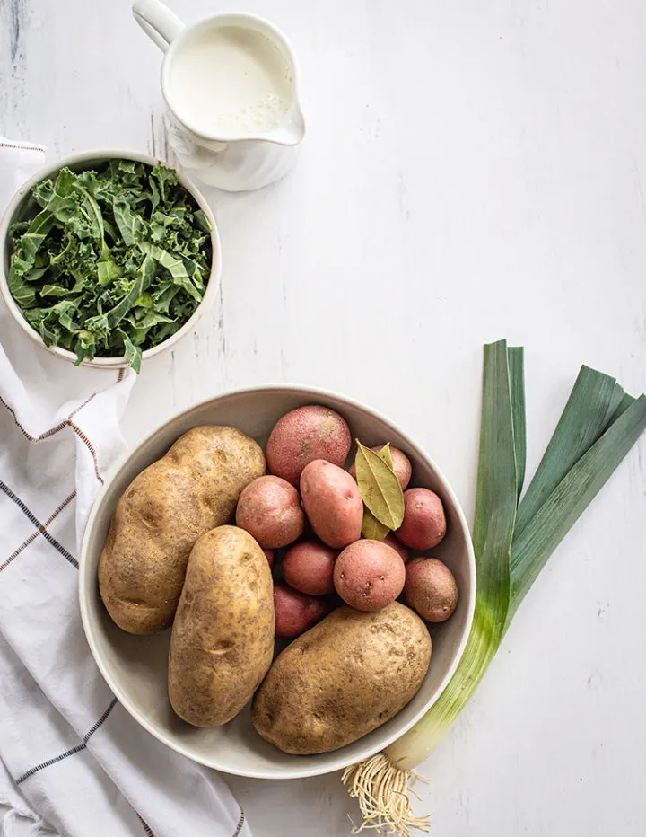 ingredients needed to make colcannon (irish mashed potatoes) on a white farmhouse table