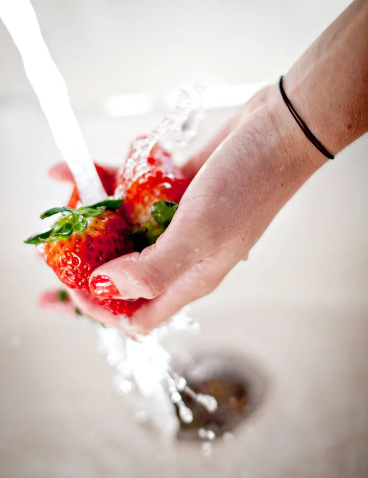 woman washing fresh strawberries before freezing strawberries