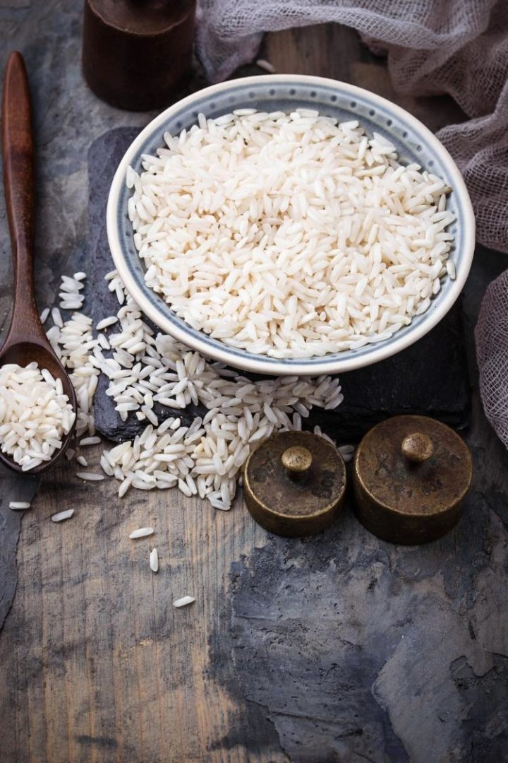 bowl of uncooked white rice on a wooden table