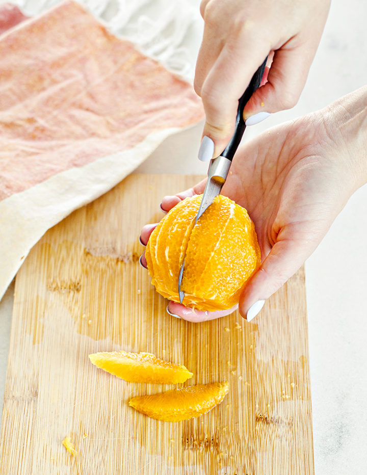 woman supreming an orange (cutting an orange into segments)