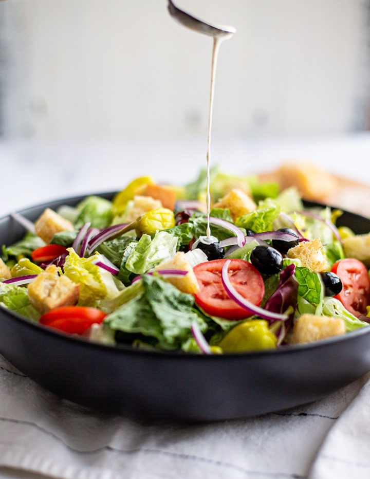 copycat olive garden salad in a black salad bowl with homemade croutons on top