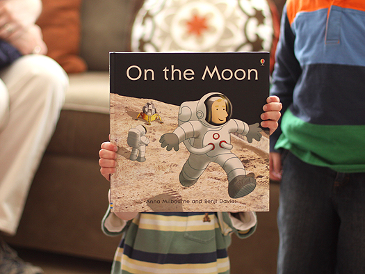 photo of a child holding a book titled On the Moon for a spaced themed birthday party