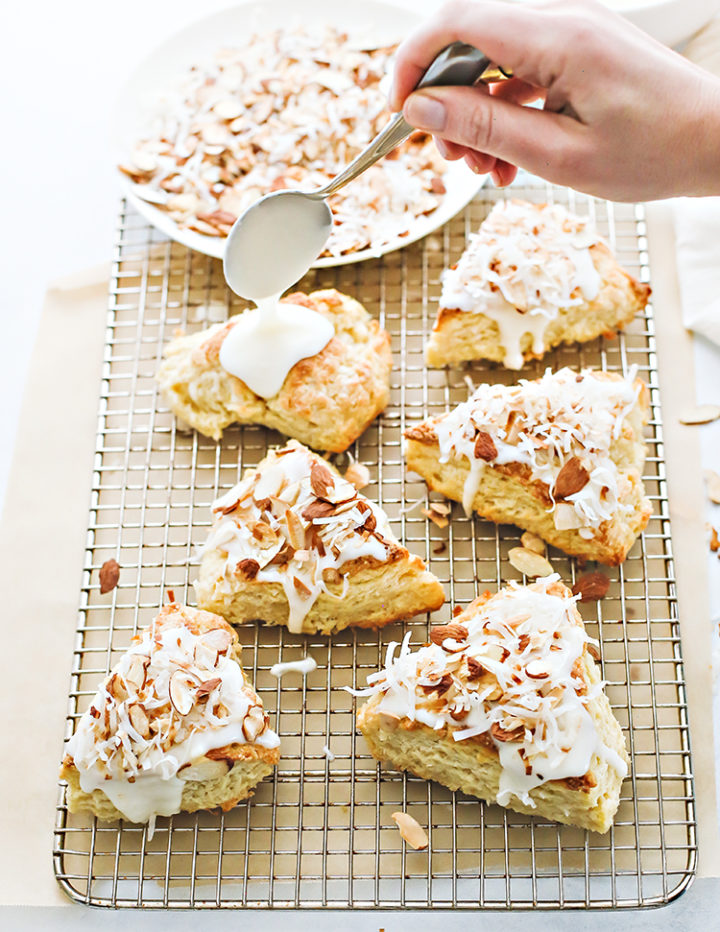 photo of coconut scones with glaze and toasted coconut on top of a cooling rack