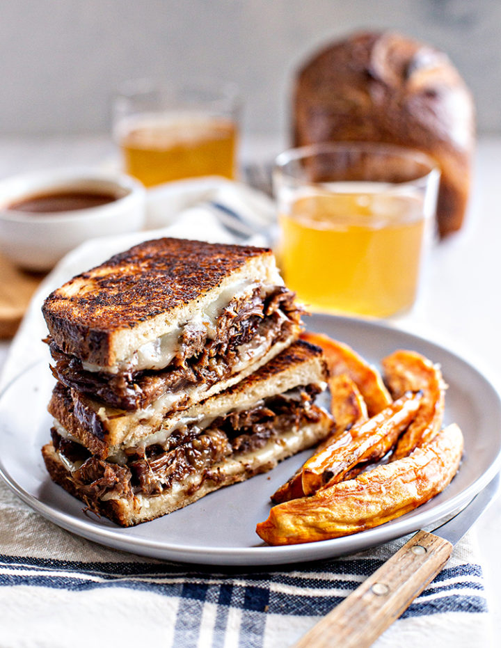 photo of french dip panini on a plate with sweet potato fries and a glass of beer