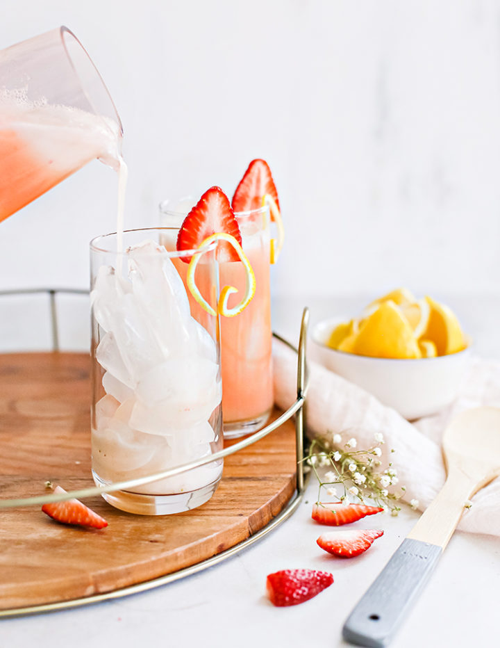 photo of pouring homemade fresh strawberry lemonade into a glass of ice