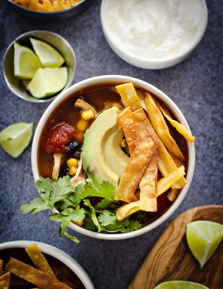 overhead shot of a white bowl of chicken tortilla soup with garnishes