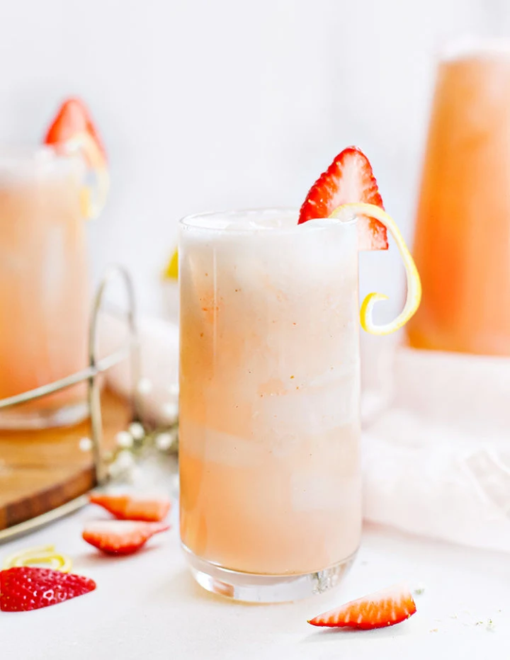 photo of glasses of fresh strawberry lemonade garnished with lemon twist and strawberry slices