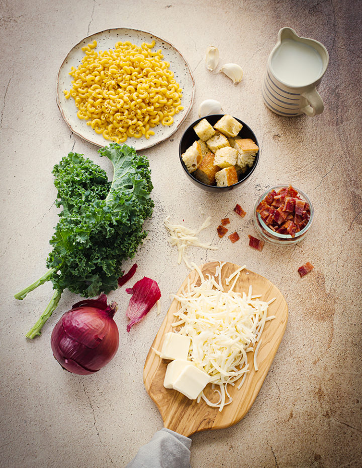 overhead shot of the ingredients to prepare white cheddar mac and cheese with kale and bacon