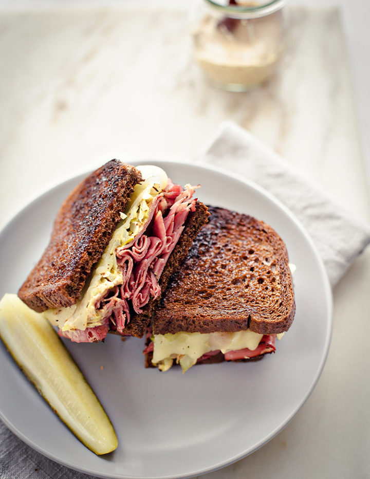 close up shot of a reuben sandwich using leftover corned beef on a plate with a pickle