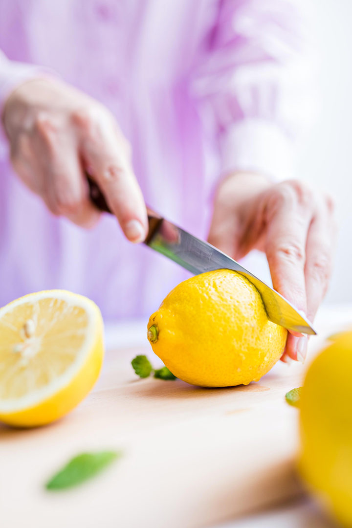 woman cutting a lemon with kitchen knives