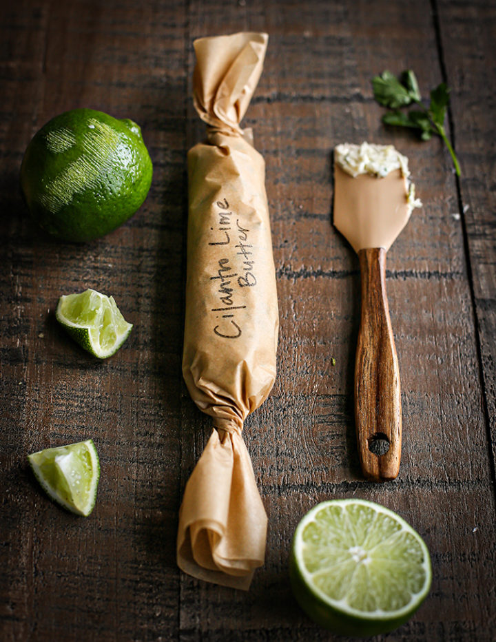 photo of cilantro lime butter rolled in parchment paper with a lime and spatula