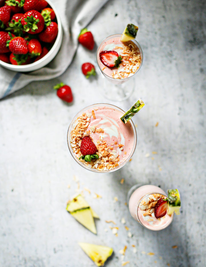 overhead photo of three glasses of Strawberry Pineapple Smoothie  with a bowl of strawberries