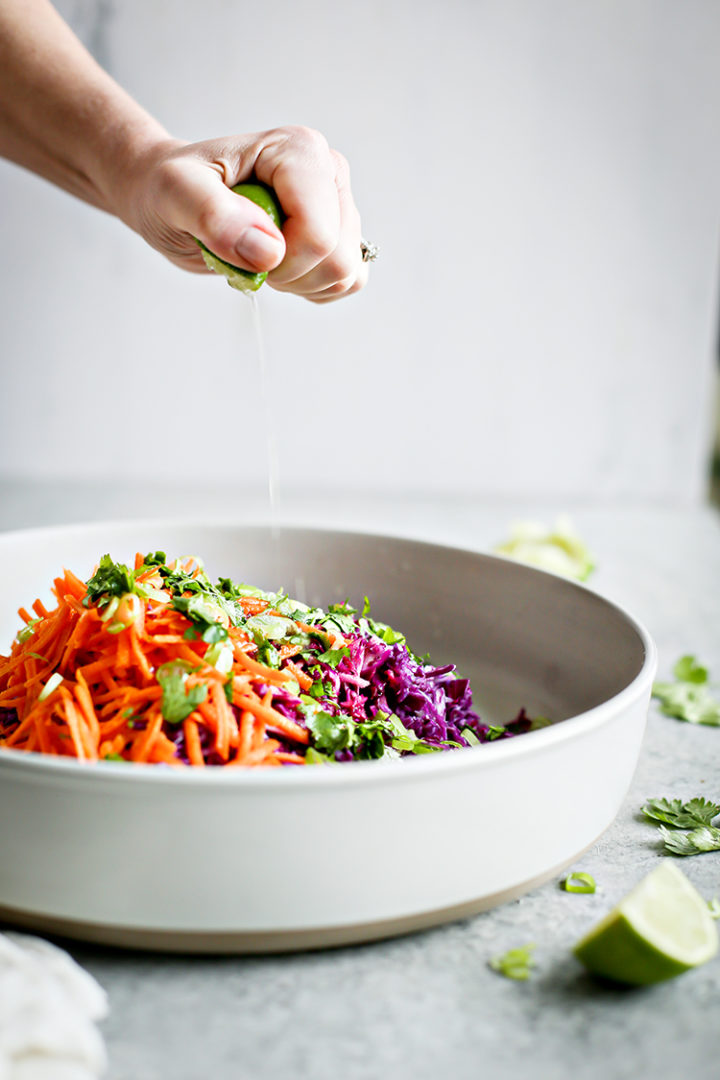 photo of woman squeezing lime into a bowl of cilantro lime slaw