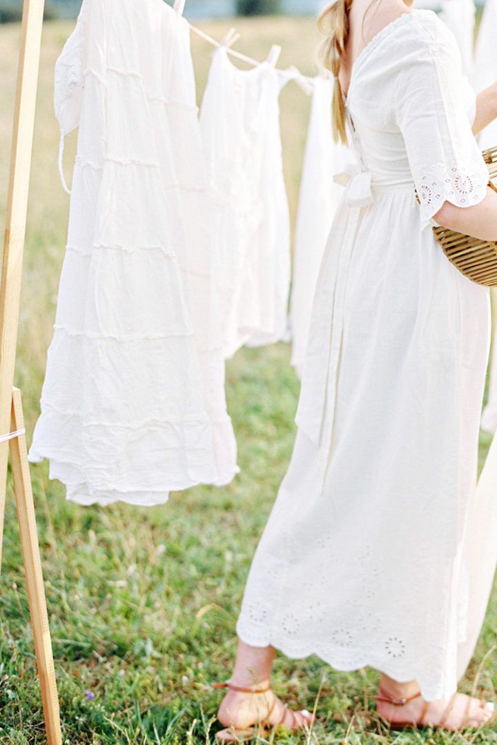 a woman hanging up white laundry on a clothes line 