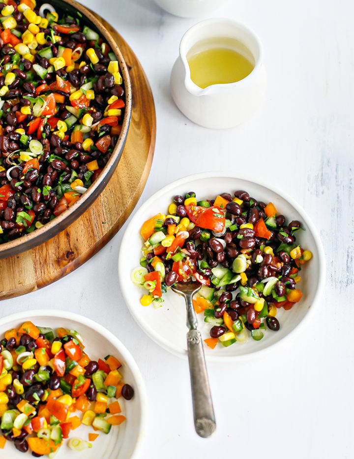overhead photo of black bean salad in bowls on a white table