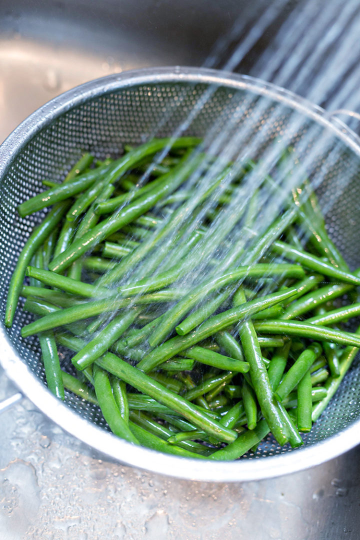 fresh green beans being rinsed to use in a vegetarian pasta salad