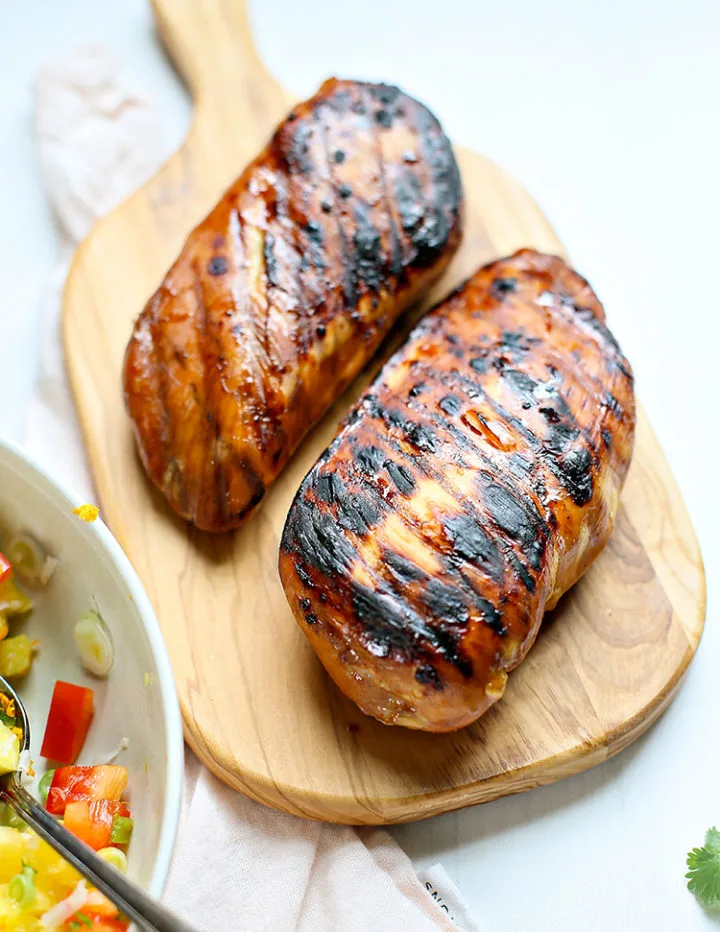 a photo of grilled chicken on a cutting board to serve with pineapple salsa and coconut rice