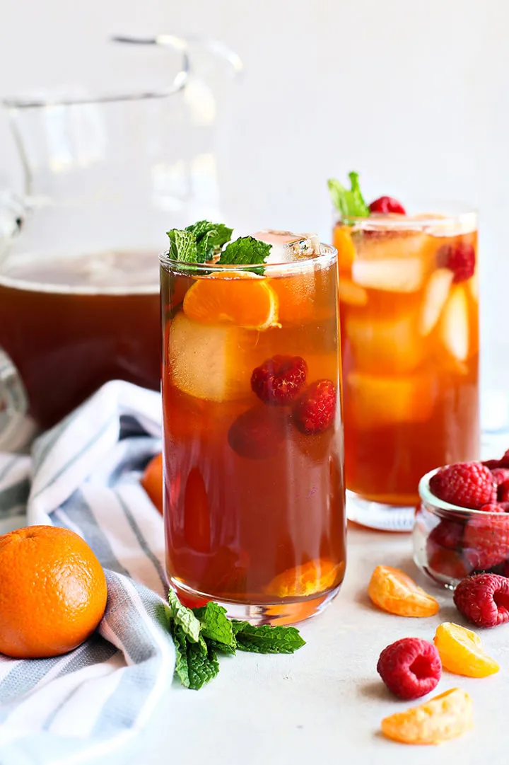 photo of a pitcher of iced tea with two glasses of raspberry iced tea on a table