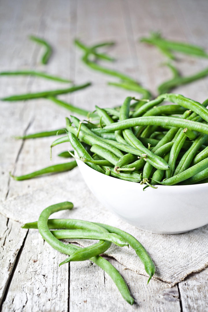 photo of green beans in a white bowl on a wooden table