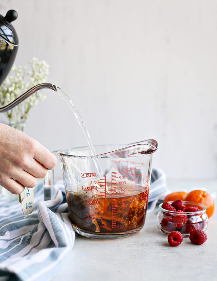 photo of a woman pouring water to make a raspberry iced tea recipe